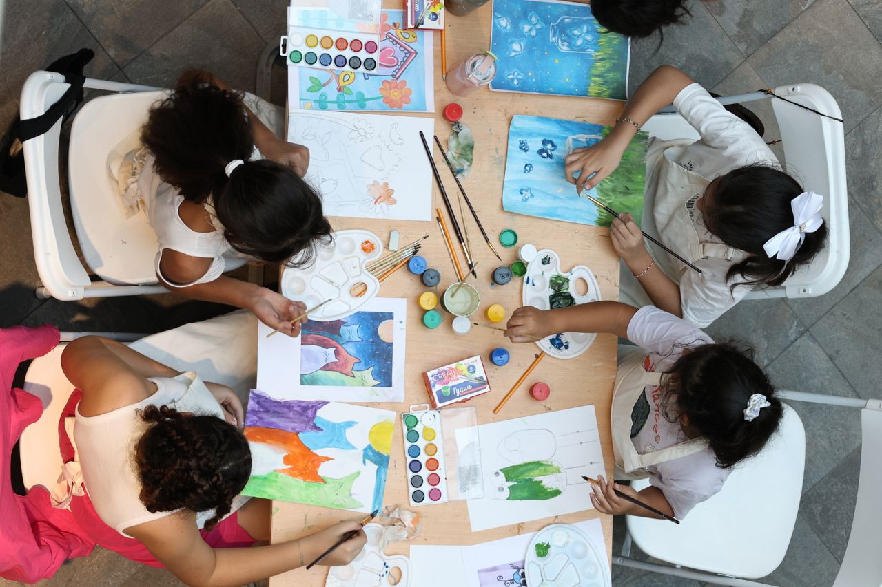 Children paint and draw in an art workshop, utilizing various colors and materials.
